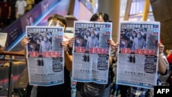 People hold up copies of the Apple Daily as they protest for press freedom.