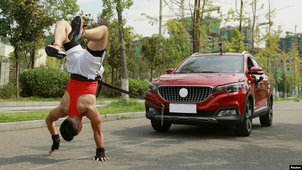 Zhang Shuang, 29, attempts to set a new Guinness World Record for "Fastest time to pull a car 50 metres walking on hands" in Nan Chong City, Sichuan Province, China September 25, 2021. (Courtesy of Guinness World Records 2021/Chen Maochao/Handout via REUTERS)