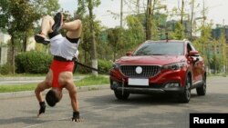 Zhang Shuang, 29, attempts to set a new Guinness World Record for "Fastest time to pull a car 50 metres walking on hands" in Nan Chong City, Sichuan Province, China September 25, 2021. (Courtesy of Guinness World Records 2021/Chen Maochao/Handout via REUTERS)