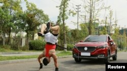 Zhang Shuang, 29, attempts to set a new Guinness World Record for "Fastest time to pull a car 50 metres walking on hands" in Nan Chong City, Sichuan Province, China September 25, 2021. Courtesy of Guinness World Records 2021/Chen Maochao/Handout via REUT