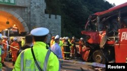 Police and firefighters work near the wreckage of a coach after it crashed into the wall of a tunnel along the Xi'an-Hanzhong expressway in Ankang, Shaanxi province, China, Aug. 11, 2017.