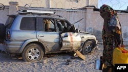 Une femme somalienne passe devant l'épave d'une voiture après une attaque à la bombe qui a tué un ingénieur travaillant avec une compagnie turque à Mogadiscio le 27 Novembre 2014. 