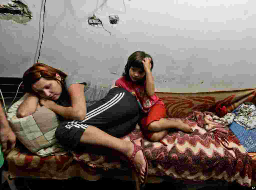 A mother and child lie on the bed in the bomb shelter in Petrovskiy district, in Donetsk, eastern Ukraine, Sept. 1, 2014. 