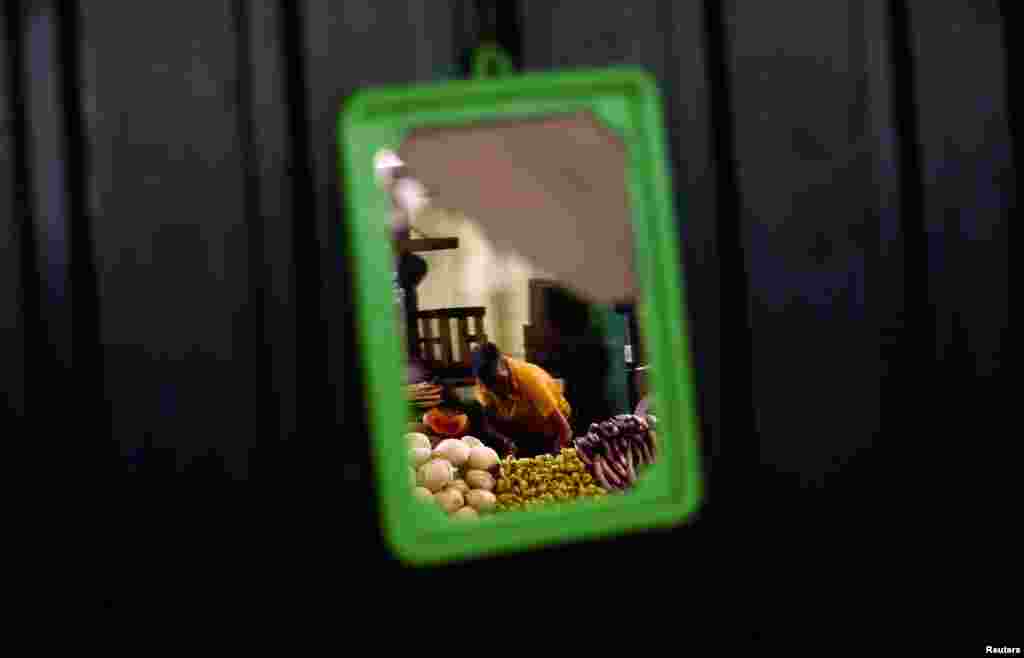 A vendor is seen in a broken mirror at a main market in Colombo, Sri Lanka.