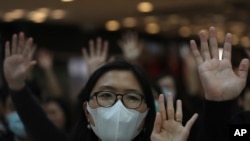 Les résidents lèvent la main pour représenter leurs cinq revendications et scandent "Adoptez le projet de loi, sauvez Hong Kong" au centre commercial IFC à Hong Kong le jeudi 21 novembre 2019. (Photo AP / Ng Han Guan)