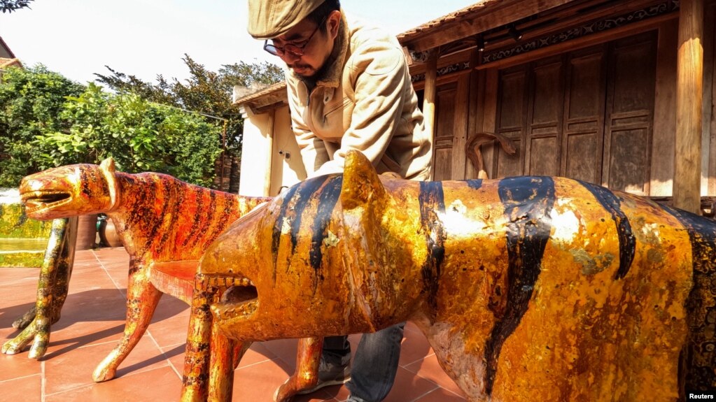 Nguyen Tan Phat stands in his yard with his Tiger carving works ahead of the Lunar New year in Hanoi, Vietnam January 18, 2022. (REUTERS/Stringer)