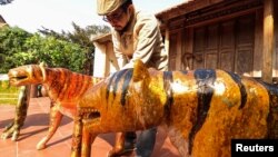 Nguyen Tan Phat stands in his yard with his Tiger carving works ahead of the Lunar New year in Hanoi, Vietnam January 18, 2022. (REUTERS/Stringer)