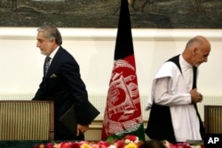 FILE - In this Sept. 21, 2014, photo, Afghanistan's then presidential candidates Abdullah Abdullah (L) and Ashraf Ghani leave after signing a power-sharing deal at the presidential palace in Kabul, Afghanistan.