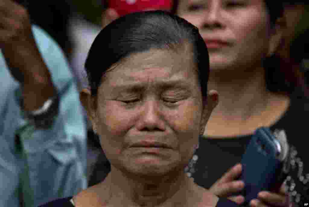 A woman has tears in her eyes as she prays at a barricade leading to Martyrs' Mausoleum in Yangon, Myanmar, Sunday, July 19, 2015. Hundreds of people gathered to pay respect at the tomb of Myanmar's Independence hero and opposition leader Aung San Suu Kyi