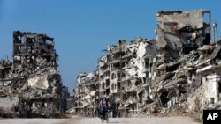 Un jeune Syrien roule à vélo dans Homs dévastée, le 26 février 2016. (AP Photo/Hassan Ammar)