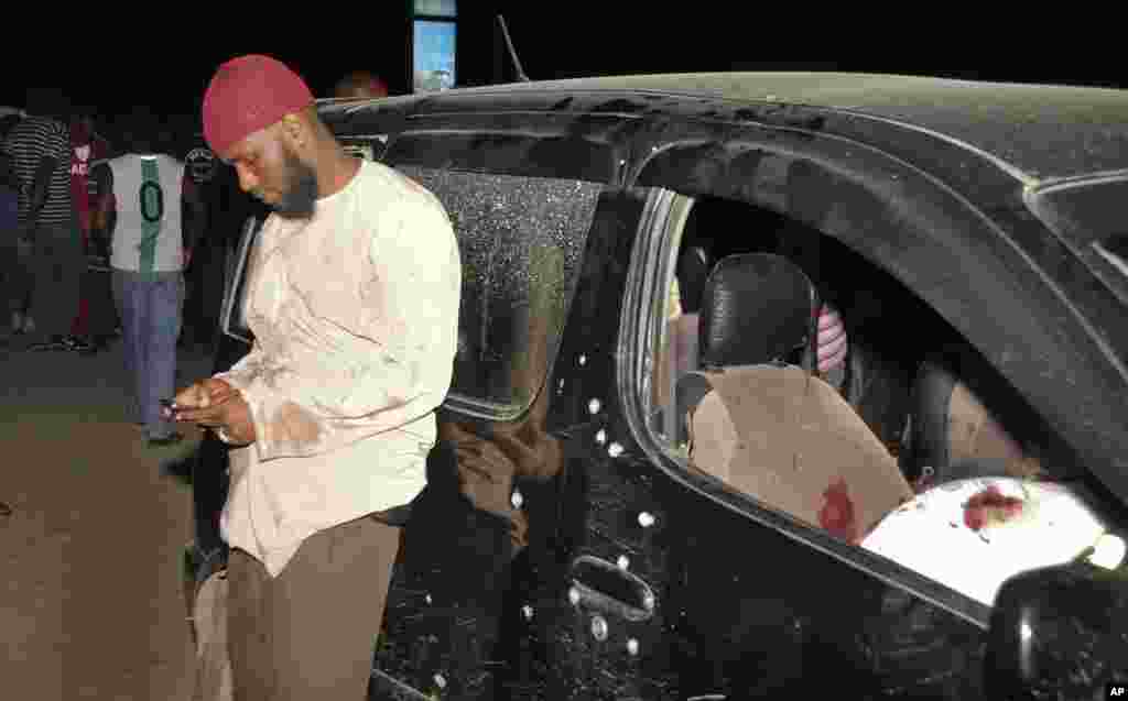 A man uses his mobile phone next to the vehicle in which Sheikh Ibrahim Ismael and three others were killed near Mombasa, Kenya, Oct. 3, 2013.
