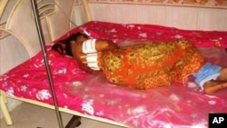 An unidentified garment worker lying on a hospital bed with multiple gunshot wounds to her back. 