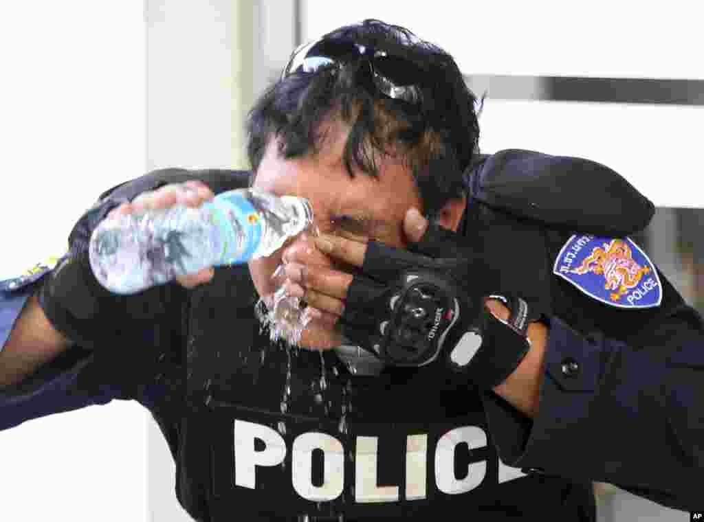A riot police officer washes tear gas from his eyes during a clash with anti-government protesters at the Labor Ministry in Bangkok, Dec. 26, 2013. 