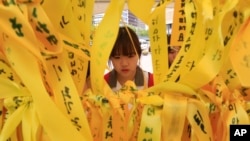 A high school student reads massages written on ribbons for the victims of the sunken ferry Sewol at a group memorial altar in Seoul, South Korea, May 15, 2014.