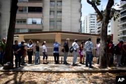 FILE - People wait in line to buy bread in Caracas, Venezuela, March 23, 2018.