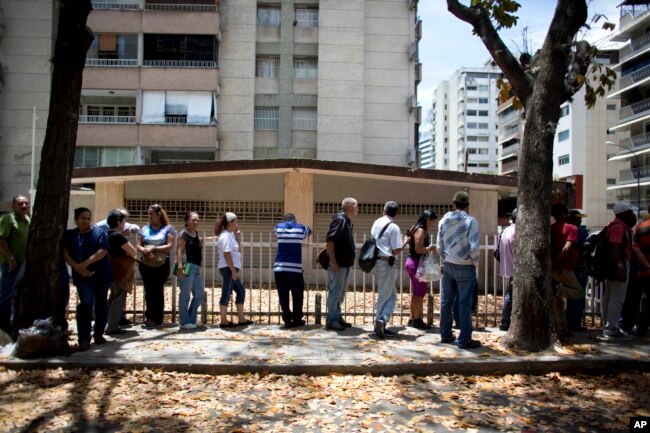 FILE - People wait in line to buy bread in Caracas, Venezuela, March 23, 2018.