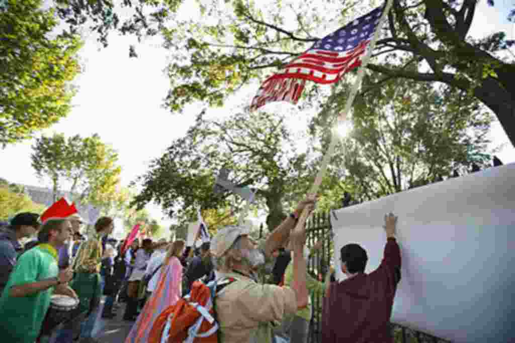 Como parte de las actividades Ocupar DC, los manifestantes ondean la bandera de la "América corporativa" en la valla frente a la Casa Blanca.