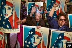 FILE - In this Feb. 19, 2017 file photo, people carry posters during a rally against President Donald Trump's executive order banning travel from seven Muslim-majority nations, in New York's Times Square.