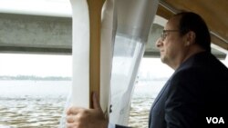 ປະທານາທິບໍດີ Francois Hollande ແຫ່ງຝຣັ່ງ ກຳລັງຂີ່ເຮືອ ຊົມທິວທັດທະເລສາບ Abidjan (17 ກໍລະກົດ 2014) 