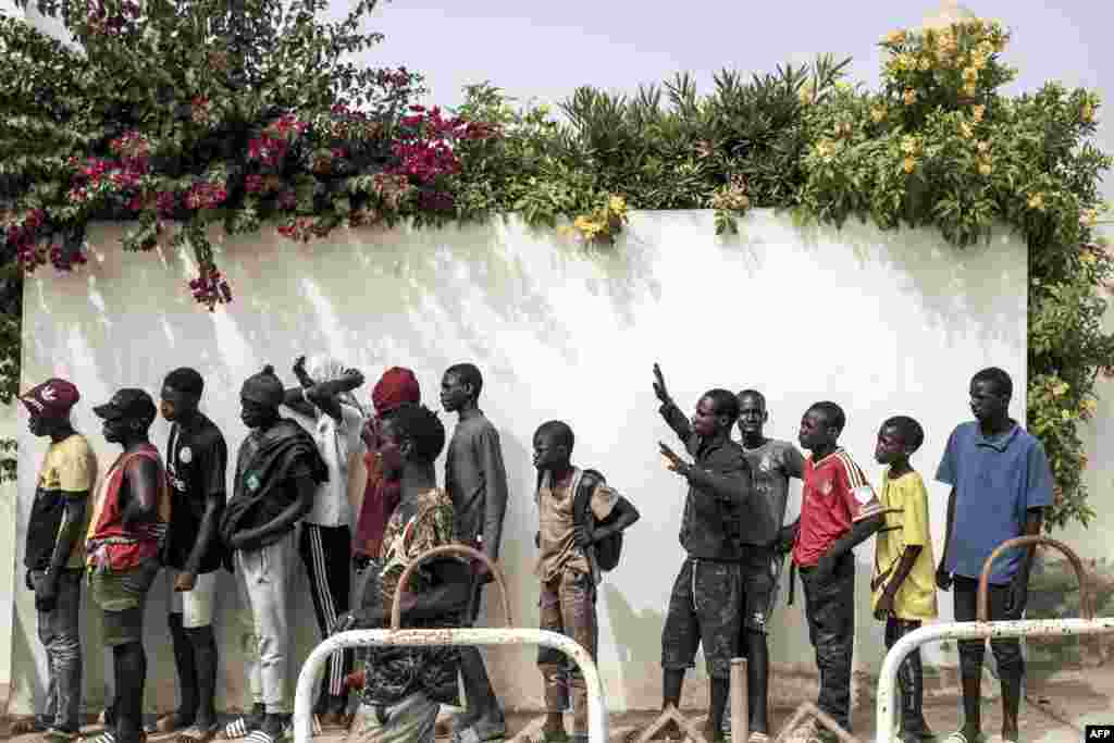 Les enfants des rues, également appelés Talibe, font la queue pour recevoir de la nourriture et des boissons distribuées par Village Pilote à Dakar, le 10 avril 2020.