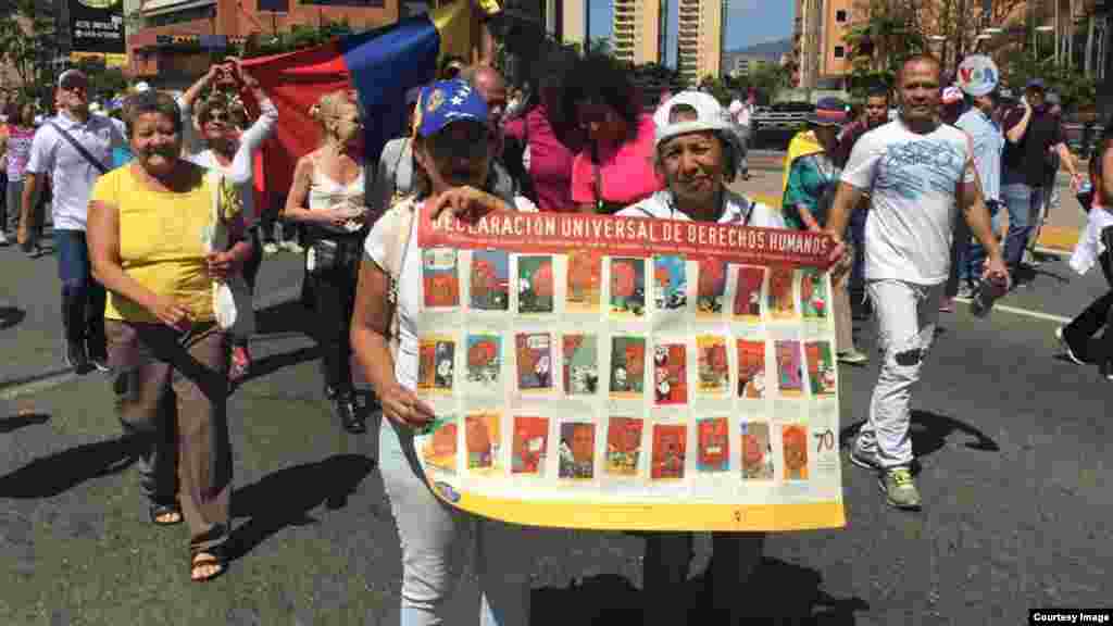 Dos mujeres sostienen un cartel durante las protestas llamadas por el presidente encargado de Venezuela, Juan Guaidó.&nbsp;