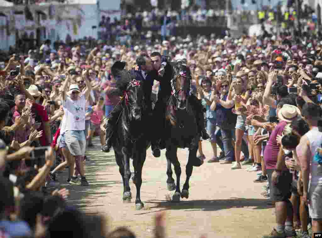 Two riders kiss while galloping during the traditional San Juan (Saint John) festival in the town of Ciutadella, on the Balearic Island of Menorca, Spain, on the eve of Saint John&#39;s Day.