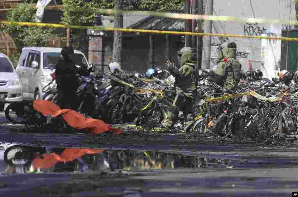 Pasukan penjinak bom dari kepolisian memeriksa serpihan sepeda motor di lokasi terjadinya ledakan di luar sebuah gereja di Surabaya, Jawa Timur, 13 Mei 2018. Serangan yang terjadi hampir secara simultan termasuk satu pelaku bom bunuh diri yang berpura-pura menjadi jemaat gereja.