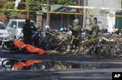 Members of police bomb squad inspect the wreckage of motorcycles at the site where an explosion went off outside a church in Surabaya, East Java, Indonesia, May 13, 2018. Almost simultaneous attacks including one by a suicide bomber disguised as a churchg