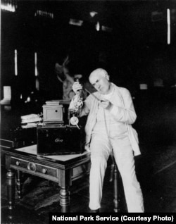 Thomas Edison in his West Orange library examining a strip of film.
