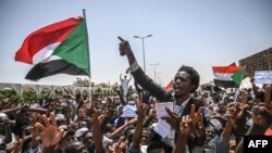 Sudanese protesters wave national flags as they chant slogans during an a sit-in outside the army headquarters in the capital Khartoum, April 26, 2019.