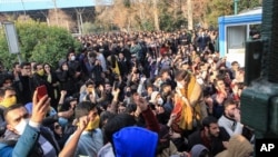 FILE - In this Saturday, Dec. 30, 2017 file photo taken by an individual not employed by the Associated Press and obtained by the AP outside Iran, university students attend a protest inside Tehran University while anti-riot Iranian police prevent them to