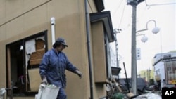 A resident cleans up tsunami debris in his destroyed house Tuesday, March 15, 2011, in Soma city, Fukushima prefecture, Japan, four days after a massive earthquake and tsunami struck the country's north east coast. (AP Photo/Wally Santana)