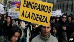 FILE - Demonstrators carry signs reading "We are forced to leave" and "They send us away" during a protest against unemployment among young people and the emigration produced by the financial crisis in Madrid, Spain, April 7, 2013.