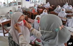 Seorang petugas kesehatan masyarakat menunjukkan cara memakai masker yang benar kepada siswa di Pondok Pesantren Daarul Rahman Jakarta, Rabu, 18 November 2020. (Foto: AP/Tatan Syuflana)