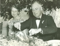 First Lady Eleanor Roosevelt watches as President Franklin D. Roosevelt carves the traditional Thanksgiving turkey during supper at Warm Springs, Georgia, November 29, 1935. (Franklin D. Roosevelt Presidential Library and Museum/White House Historical Ass