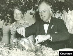 First Lady Eleanor Roosevelt watches as President Franklin D. Roosevelt carves the traditional Thanksgiving turkey during supper at Warm Springs, Georgia, November 29, 1935. (Franklin D. Roosevelt Presidential Library and Museum/White House Historical Ass