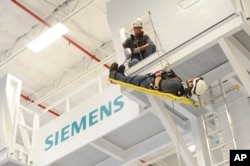 FILE - Siemens Energy wind trainers demonstrate a safety and rescue training simulation at Siemens Energy's 40,000 square-foot, state-of-the-art wind service training center in Orlando, Florida, Sept. 19, 2013.