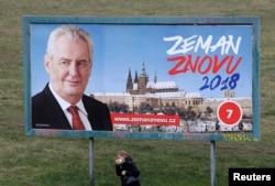 A woman walks past a presidential election campaign poster of incumbent Milos Zeman in Prague, Czech Republic, Jan. 11, 2018. The poster reads: "Zeman again 2018".