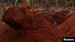 A worker stands beside an excavator digging for ore at Mobi Jaya Persada's nickel mining area at Dampala village in Marowali, central Sulawesi, Indonesia, Jan. 12, 2014.