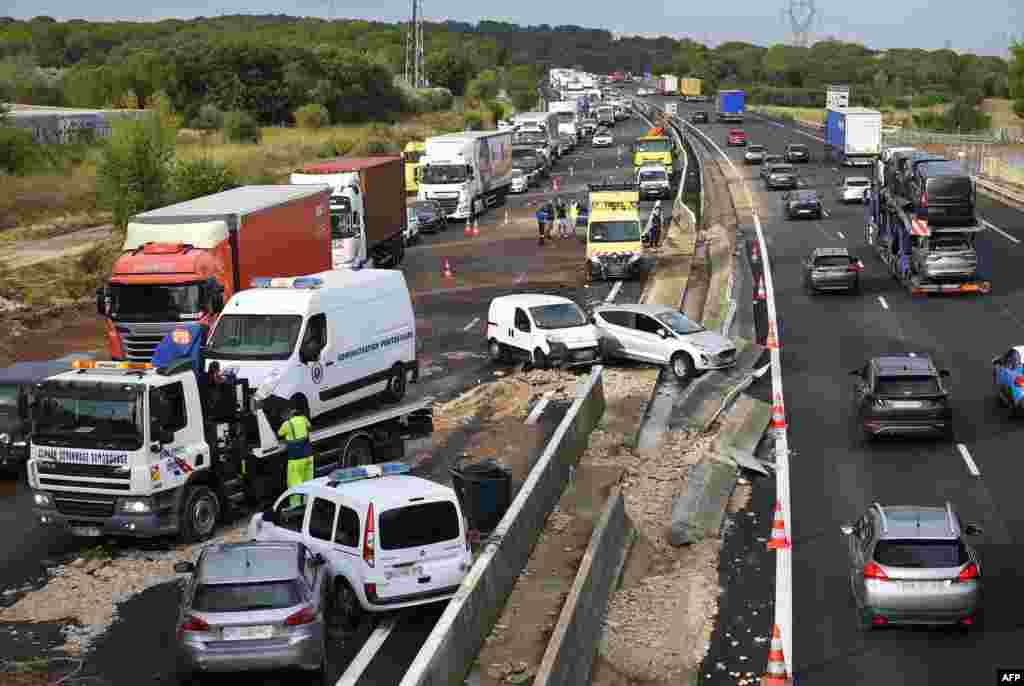 Traffic flows past the wreckage of vehicles on the A9 highway, in Bernis, southern France, after heavy rains struck the region.