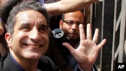 Egyptian television satirist Bassem Youssef waves to his supporters as he enters Egypt's state prosecutors office to face charges for allegedly insulting Islam and the country's leader, in Cairo, Mar. 31, 2013.