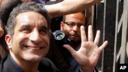 Figur televisi Mesir Bassem Youssef, yang terkenal akan konten politik satirnya, melambaikan tangan kepada para pendukungnya ketika ia memasuki kantor kejaksaan Mesir untuk menjalani pemeriksaan atas dugaan penghinaan terhadap Islam dan pemimpin negara tersebut, pada 31 Maret 2013. (Foto: AP)