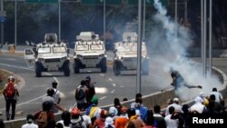 Pengunjuk rasa dari kelompok oposisi menghadapi kendaraan militer dekat Pangkalan Udara Generalisimo Francisco de Miranda “La Carlota” di Caracas, Venezuela, 30 April 2019.
