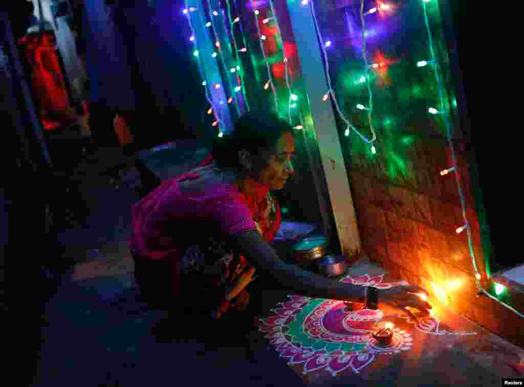 بھارت کے شہر ممبئی میں ایک ہندو عورت دیوالی کے جشن کے لیے گھر کو سجا رہی ہے