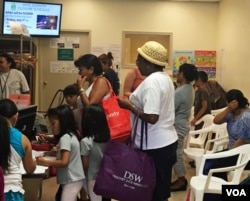 Virginia residents fill bags with free groceries at the Arlington Food Assistance Center in Arlington, Virginia, June 28, 2016. (VOA/C. Maddux)