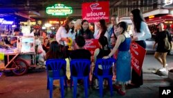 Pauline Ngarmpring, left, speaks with workers of a roadside massage parlor during an election campaign in Bangkok, Feb. 13, 2019.