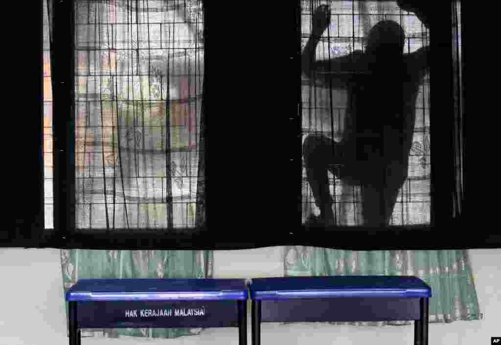 An election volunteer cleans the glass windows at a voting center in Pekan, Pahang state, Malaysia.