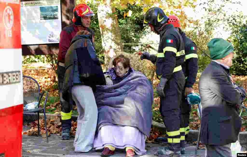 Firefighters take care of a woman following an earthquake in Norcia, Italy, Oct. 30, 2016.