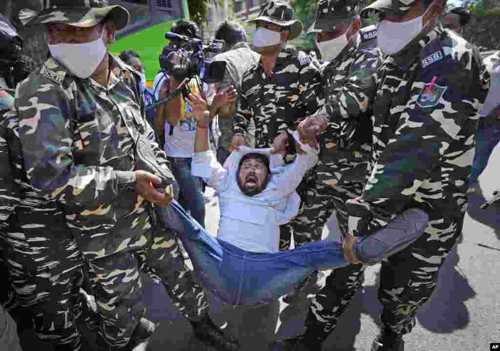 Paramilitary force soldiers detain an activist protesting against Sunday&#39;s killing of four farmers in Uttar Pradesh state after being run over by a car owned by India&#39;s junior home minister, in New Delhi.