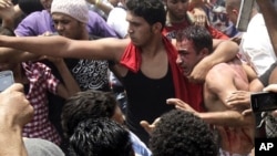A protester protects a detained "thug" from other protesters who want to beat him during clashes between Islamist protesters and armed "thugs" in Cairo May 2, 2012.